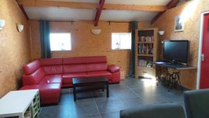 a living room with a red couch and a tv at Minicamping In de Bocht in Grijpskerke