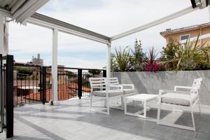 een patio met witte stoelen en tafels op een balkon bij Meg Lifestyle Hotel & Apartaments in Riccione