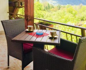 drewniany stół na balkonie z dwoma kubkami i miskami w obiekcie Bovec Holiday House w mieście Bovec