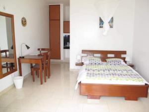 Schlafzimmer mit einem Bett, einem Tisch und einem Schreibtisch in der Unterkunft Hôtel Maisons-Sifa in Butare