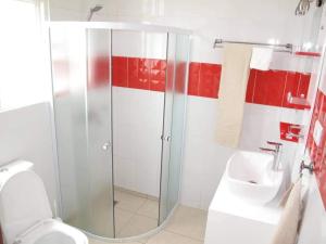 a bathroom with a shower and a toilet and a sink at Hôtel Maisons-Sifa in Butare