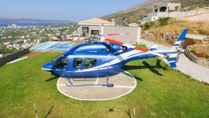 un helicóptero azul sentado en la parte superior de un campo de césped en Villa Kedria with a panoramic ocean view, en Suda