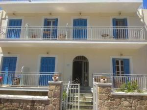 a white house with blue windows and a balcony at Panos Studios in Poros