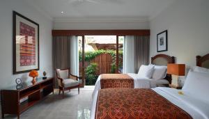 a hotel room with two beds and a chair at Kama Village by Nakula in Sanur