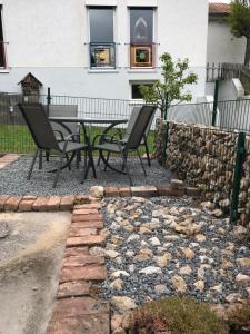 un patio con mesa, sillas y pared de piedra. en Alte Schule 1, en Kall