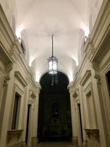 un corridoio vuoto con lampadario a braccio in un edificio di B&B Roma Royal Residence a Roma
