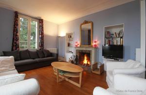 sala de estar con sofá, mesa y chimenea en Normandie 12 couchages, en LʼAigle