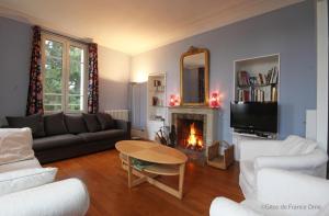 a living room with a couch and a table and a fireplace at Normandie 12 couchages in LʼAigle