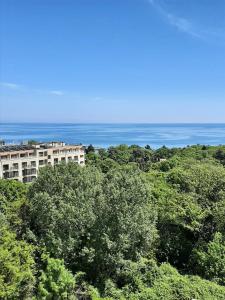金沙的住宿－Vesta Riviera - Free Parking，树中间的一座建筑,背景是大海
