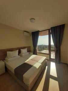 a bedroom with a large bed and a large window at Vesta Riviera - Free Parking in Golden Sands