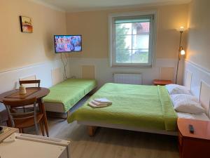 a room with two beds and a table and a television at Apartamenty i Pokoje Magnolia in Dźwirzyno