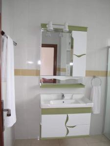 a white bathroom with a sink and a mirror at Hôtel Maisons-Sifa in Butare