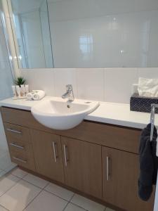 W łazience znajduje się biała umywalka i lustro. w obiekcie Wallaroo Marina Executive Apartments w mieście Wallaroo
