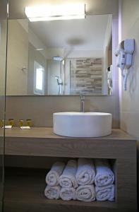 a bathroom sink with towels hanging on the wall at Elysee Hotel in Sitia