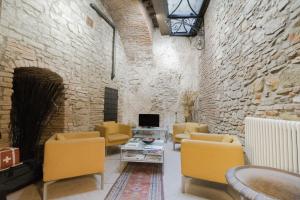 salon z żółtymi krzesłami i kamienną ścianą w obiekcie La Corte Del Re Suite & Rooms Arezzo w Arezzo