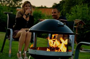 a man and woman sitting next to a fire pit at La Villa Belle in Belle-et-Houllefort
