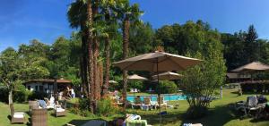 a resort with a pool with chairs and umbrellas at Garni Villa Siesta Park in Losone