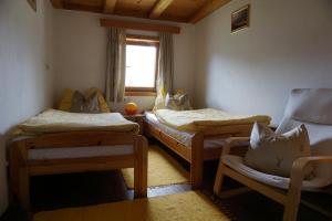 Zimmer mit 2 Betten, einem Stuhl und einem Fenster in der Unterkunft Bauernhaus Heisenbauer in Neukirchen am Großvenediger