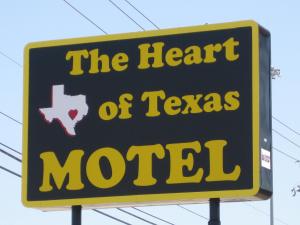 a yellow and white sign with a cat on top of it at Heart of Texas Motel in Austin