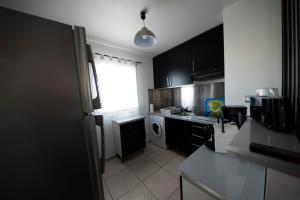 uma pequena cozinha com armários pretos e uma janela em Eden Appartement, T2 49m2, 4 pers vue mer, piscine em Saint-Gilles-les-Bains