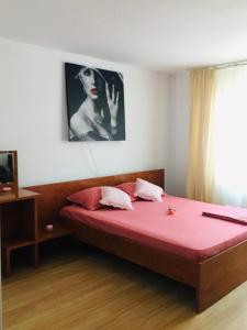 Un dormitorio con una cama con sábanas rojas y una foto de una mujer en Casa Kito en Constanza