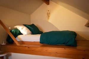 a bed with two green pillows on a wooden shelf at BC bed en comfort in Bilzen