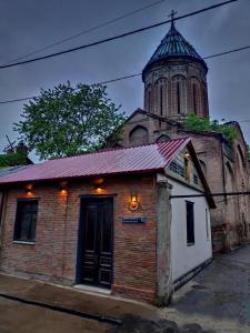 un ancien bâtiment en briques avec une tour sur une église dans l'établissement 3 Heritage Rooms, à Tbilissi