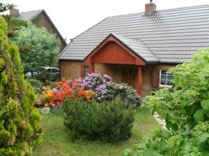 dom z ogrodem kwiatów przed nim w obiekcie Wakacje nad jeziorem w mieście Chłopowo