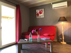 a living room with a red couch and a table with flowers at Domaine de Label, Spa, massages in La Salvetat