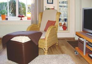 a living room with a wicker chair and a television at Ferienwohnung Nowara in Krummhörn +12 photos