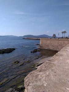 a stone wall with a rock wall next to a body of water at Piazza Ginnasio Affittacamere in Alghero