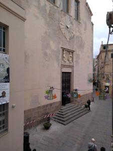 a stone building with a clock on the side of it at Piazza Ginnasio Affittacamere in Alghero