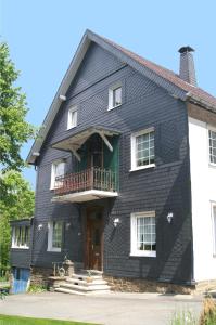 a black house with a balcony at Pension Oberberg in Lindlar