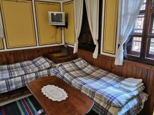 a room with two beds and a table and a tv at Hadji Neikovi Guest Houses in Koprivshtitsa