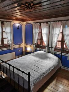 a bedroom with a bed with blue walls and windows at Hadji Neikovi Guest Houses in Koprivshtitsa