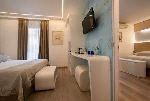 a hotel room with a bed and a tv on the wall at Hotel Daniele in Lignano Sabbiadoro