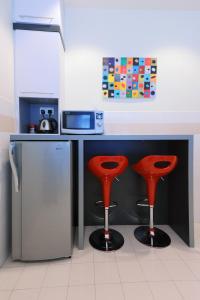 a kitchen with a counter with two red stools at The One Vacation Home in Melaka