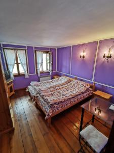 a bedroom with purple walls and a large bed at Hadji Neikovi Guest Houses in Koprivshtitsa