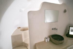 a bathroom with a toilet with a green seat and a mirror at Menias Cave House in Oia