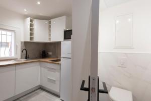 a white kitchen with white cabinets and a sink at APPARTEMENT 1 NEUF sur le port à coté de la plage in Saint-Raphaël +8 photos
