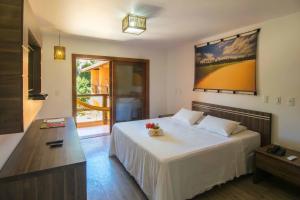 a bedroom with a large white bed with flowers on it at Pousada Vila do Dengo in Itacaré