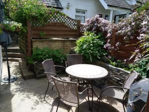 a patio with a table and chairs and flowers at Meadowside Cottage in Bassenthwaite Lake