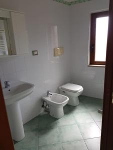 bagno bianco con servizi igienici e lavandino di Petra Marina Maris a Pisciotta