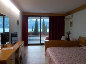 a hotel room with a bed and a desk with a television at Hotel Laura Christina in Malcesine