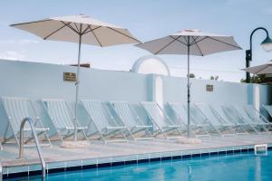 eine Reihe von Stühlen und Sonnenschirmen neben einem Pool in der Unterkunft Appartamento presso Residence Verdemare in Àrbatax