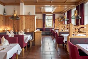 a dining room with tables and red chairs at Hotel Neuer am See in Prien am Chiemsee