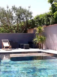 a swimming pool with a chair next to a wall at Appartement Pérols Centre in Pérols