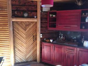 uma cozinha com armários vermelhos e uma porta de madeira em Bondari - countryside experience near Rēzekne em Reiki