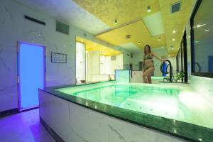 a woman standing in a bath tub in a bathroom at Hotel Diplomat Palace in Rimini