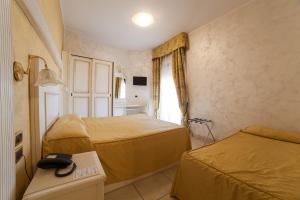 a hotel room with two beds and a phone on a table at Hotel Diplomat Palace in Rimini